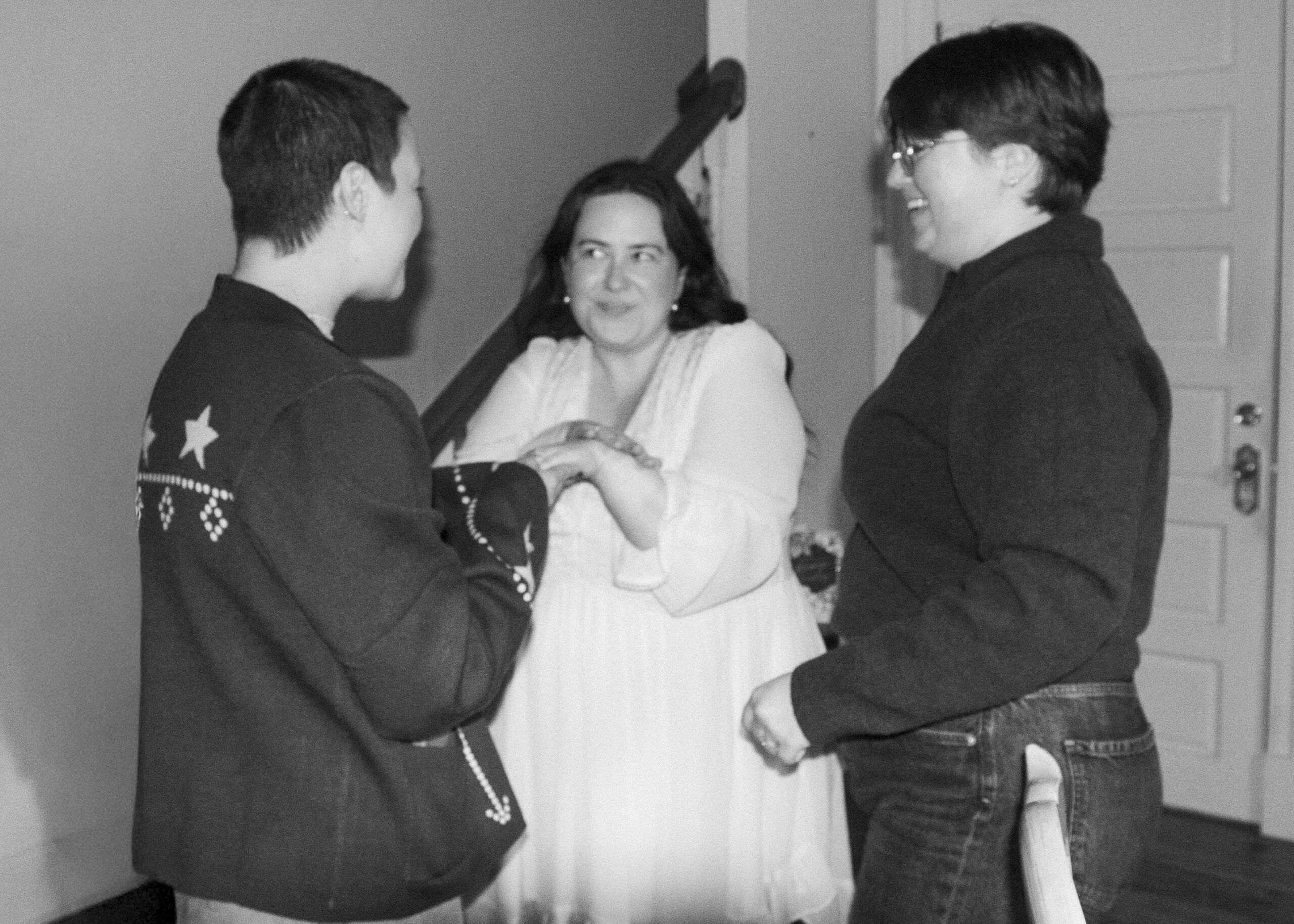 A couple shows a friend the new engagement ring at an engagement party, the photo is blurry and candid