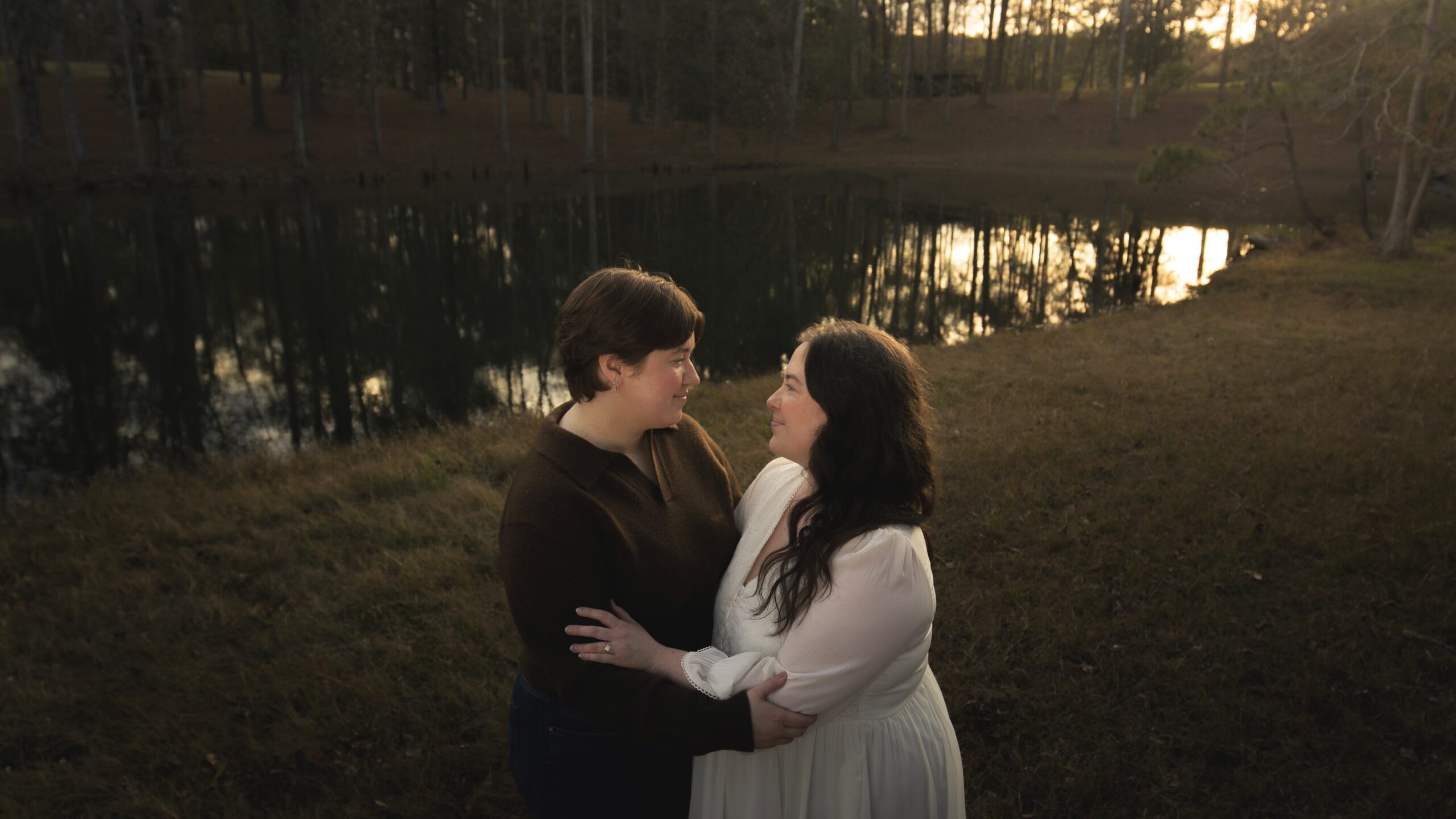 Two queer lovers gazing at each other by an evening lake, filmy and soft