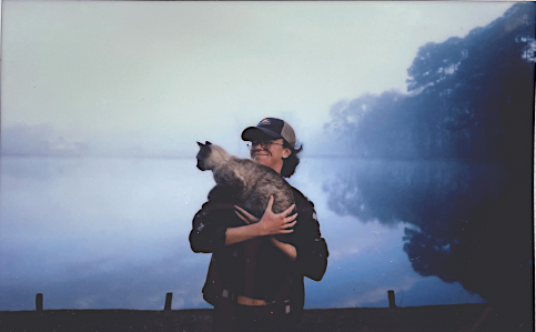 Polaroid photo of Theo and a cat by a foggy lake