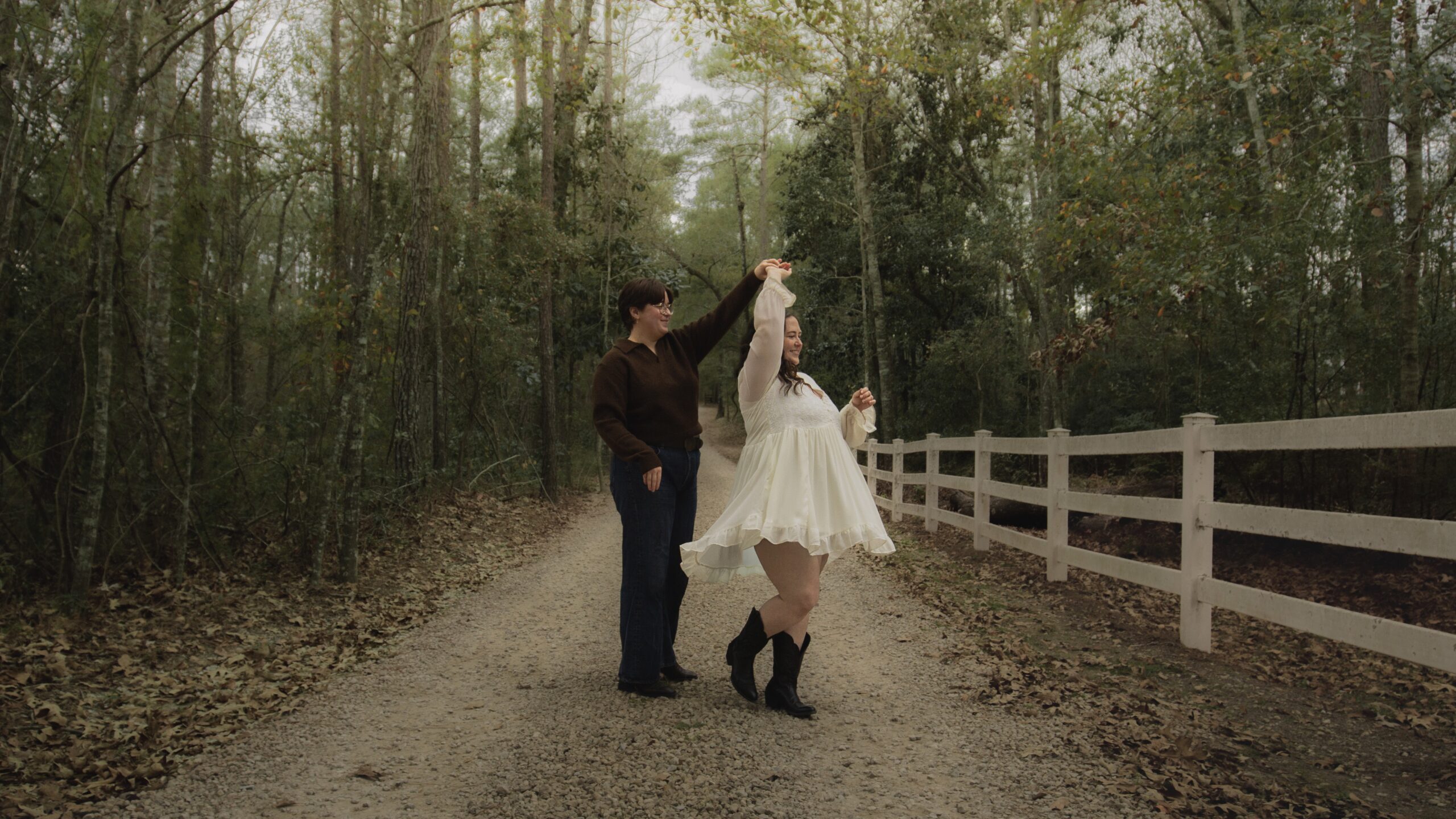 Two queer people dancing on a dirt lane in south georgia, just after getting engaged