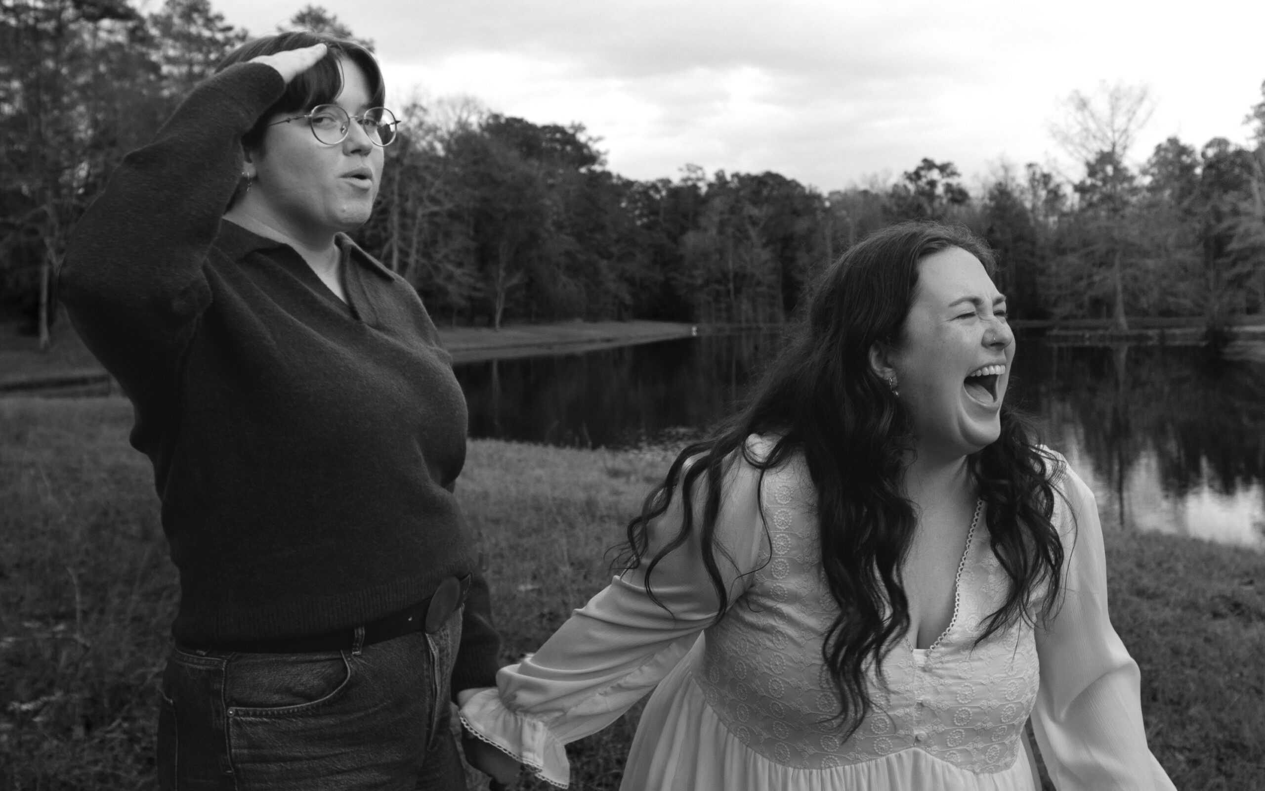 A lesbian couple cheers and celebrates about getting engaged, next to a beautiful lake in Moultrie GA