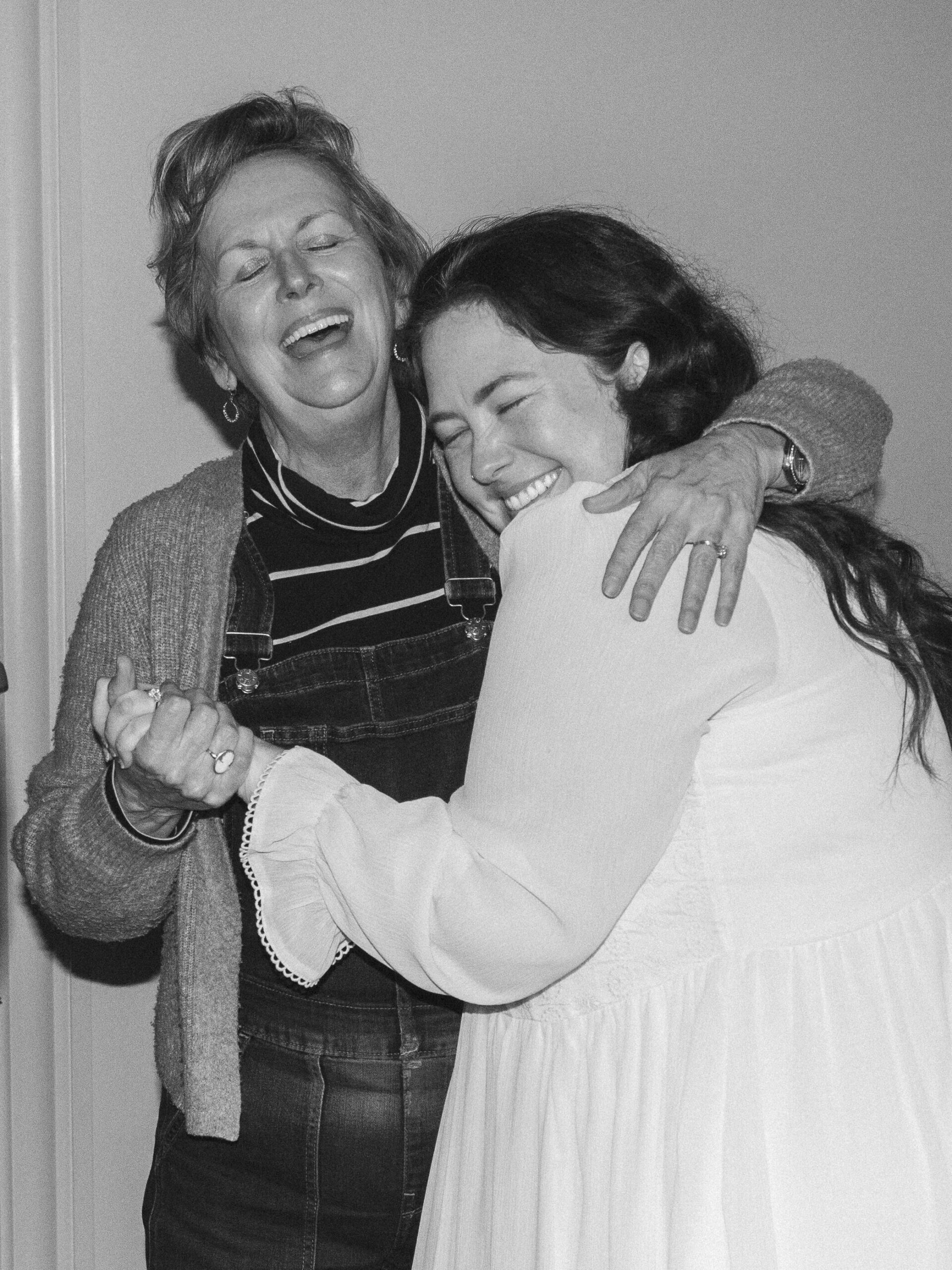 A mother and her daughter hug, laugh, and celebrate her engagement